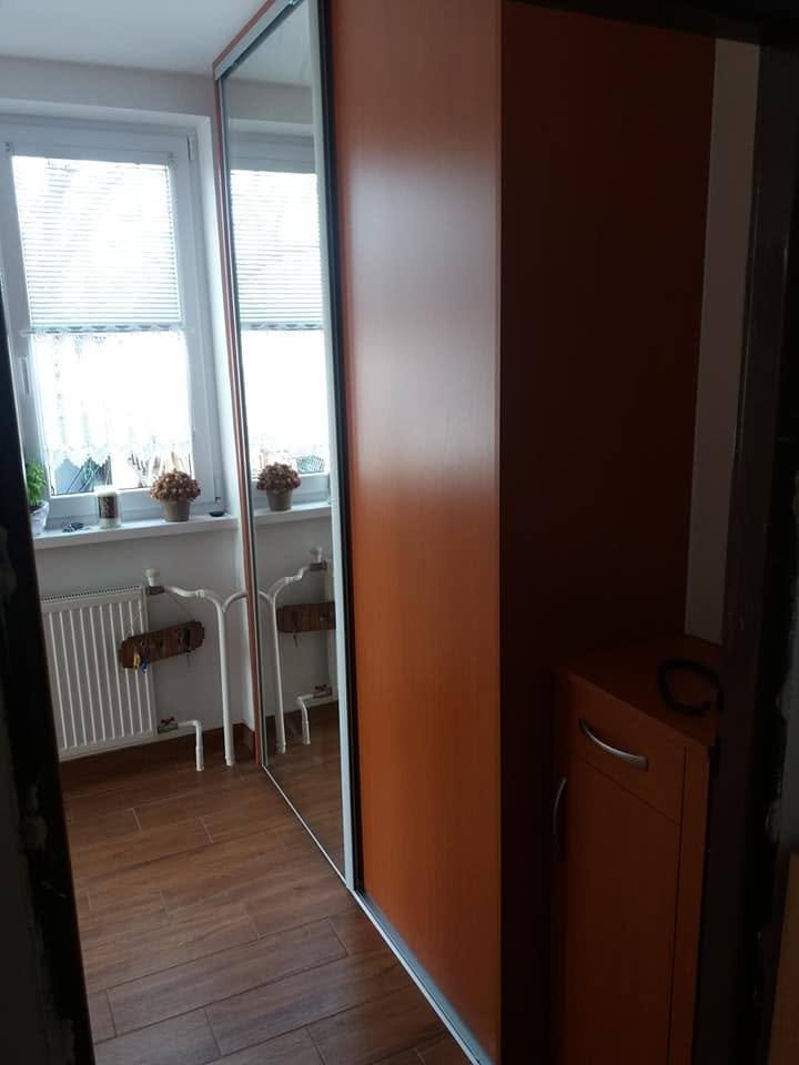 Skriňa s čerešňovými dverami pri okne s radiátorom v izbe.