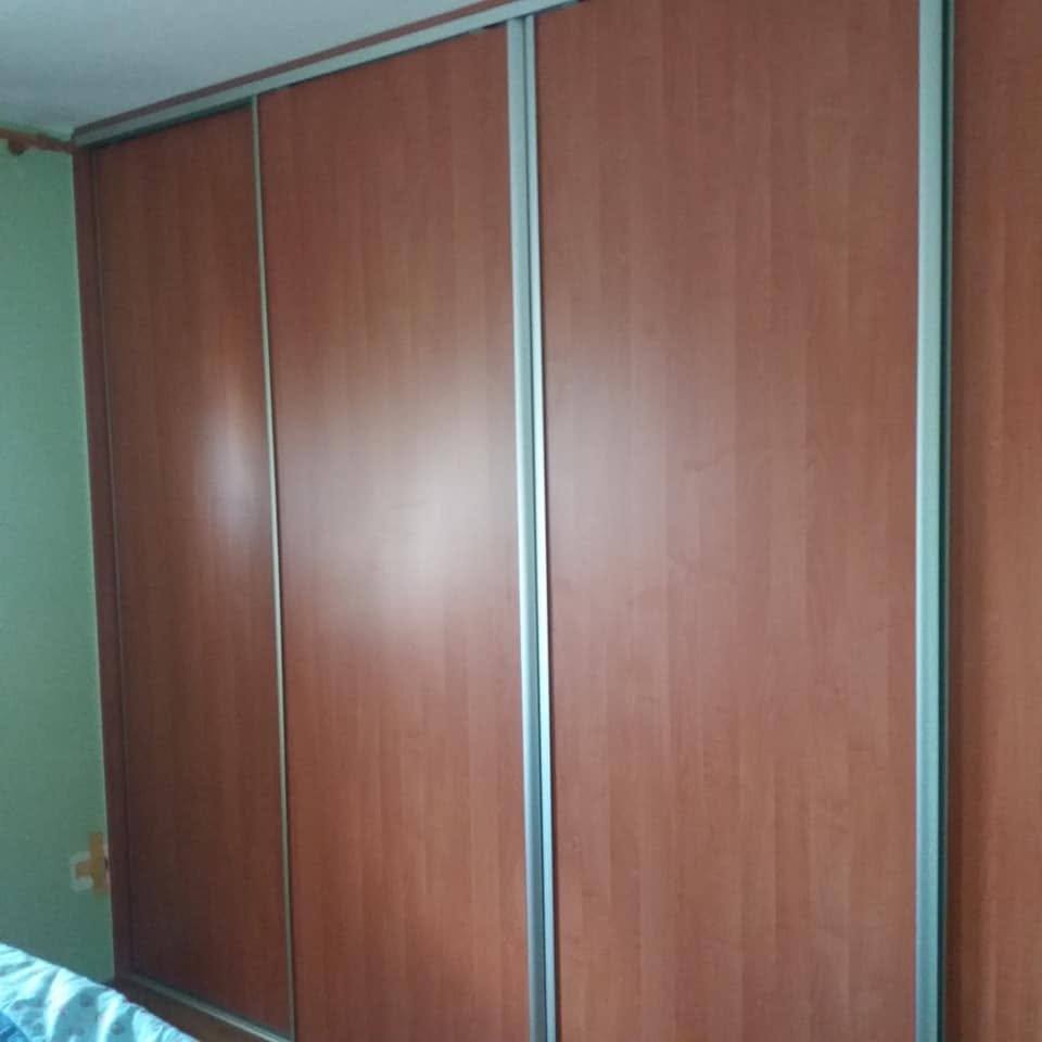 Einbaukasten mit Türen in Kirschdekor über dem Bett im Schlafzimmer.