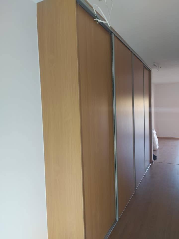 Skriňa s posuvnými dverami v svetlejšom odtieni dreva pri chodbe.