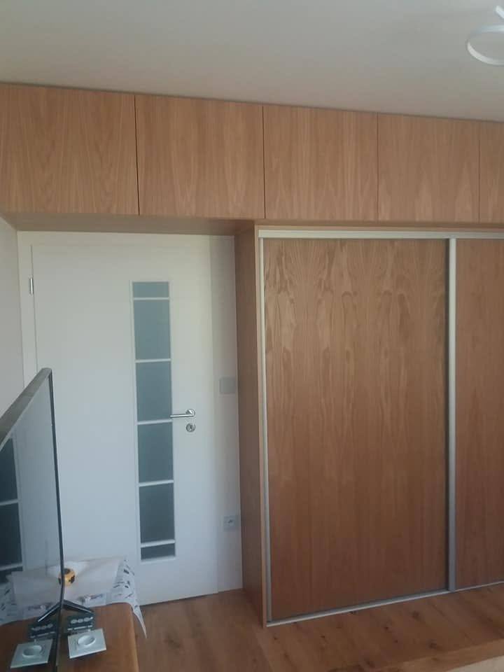 Kasten mit Kirschholztüren und schmalem Glaseinsatz an der Wand.