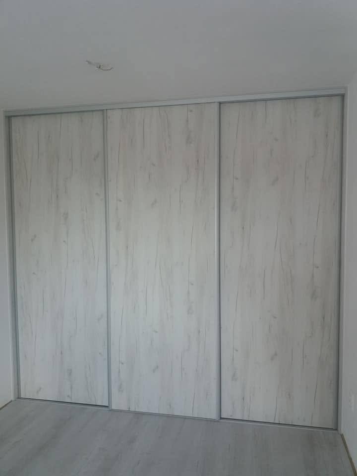 Vstavaná skriňa s troma posuvnými dverami v bielenom drevodekore.