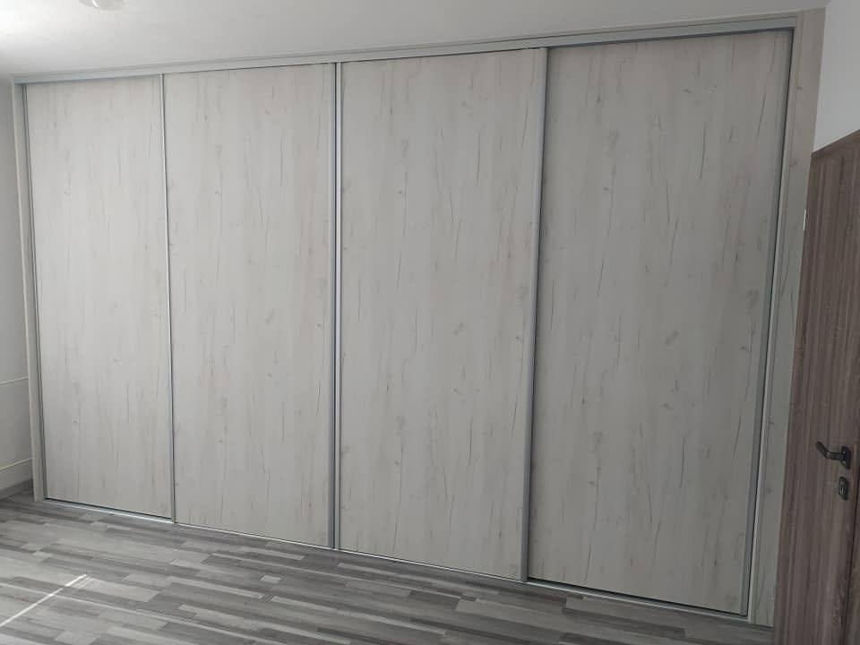 Breiter Kasten mit drei Türen in hellem Holzdekor im Zimmer.