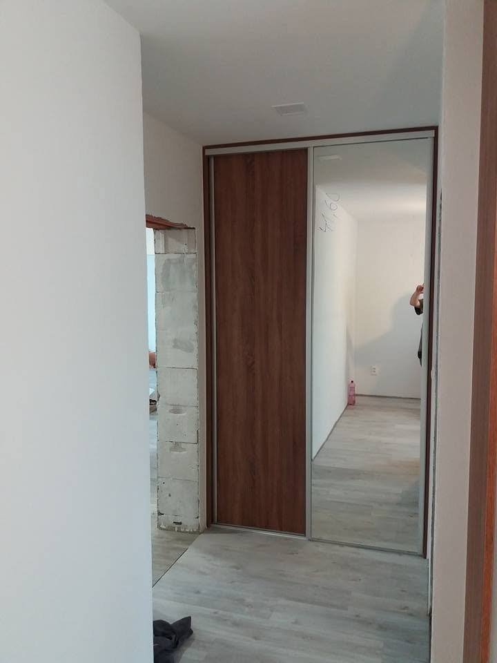 Einbaukasten mit Spiegel- und Holzdekor-Schiebetür im Vorzimmer.