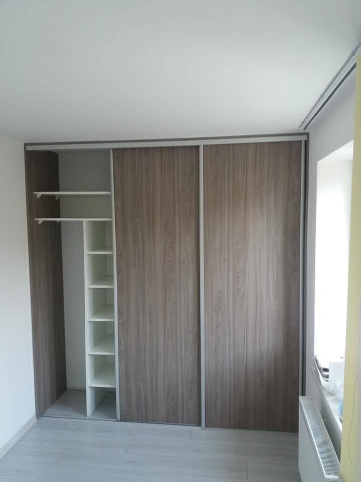 Geöffneter Kasten mit Kleiderstange und Böden am Fenster.