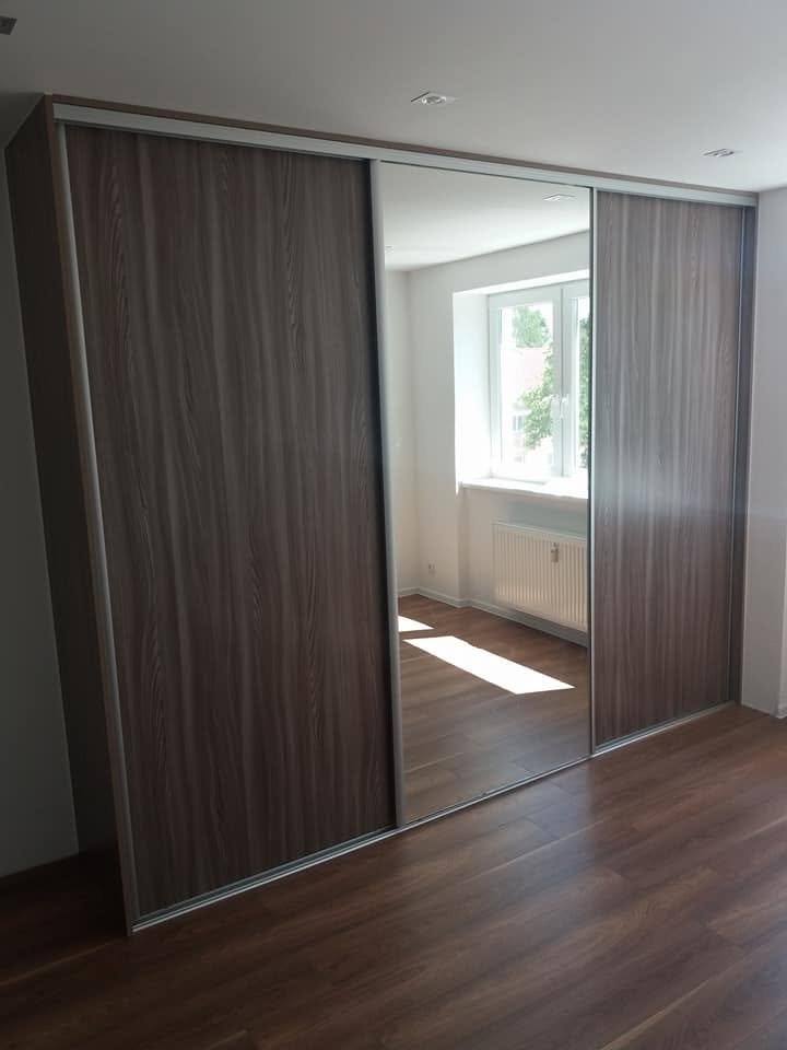 Geschlossener Kasten mit dunklen Nussbaum-Türen am Fenster.