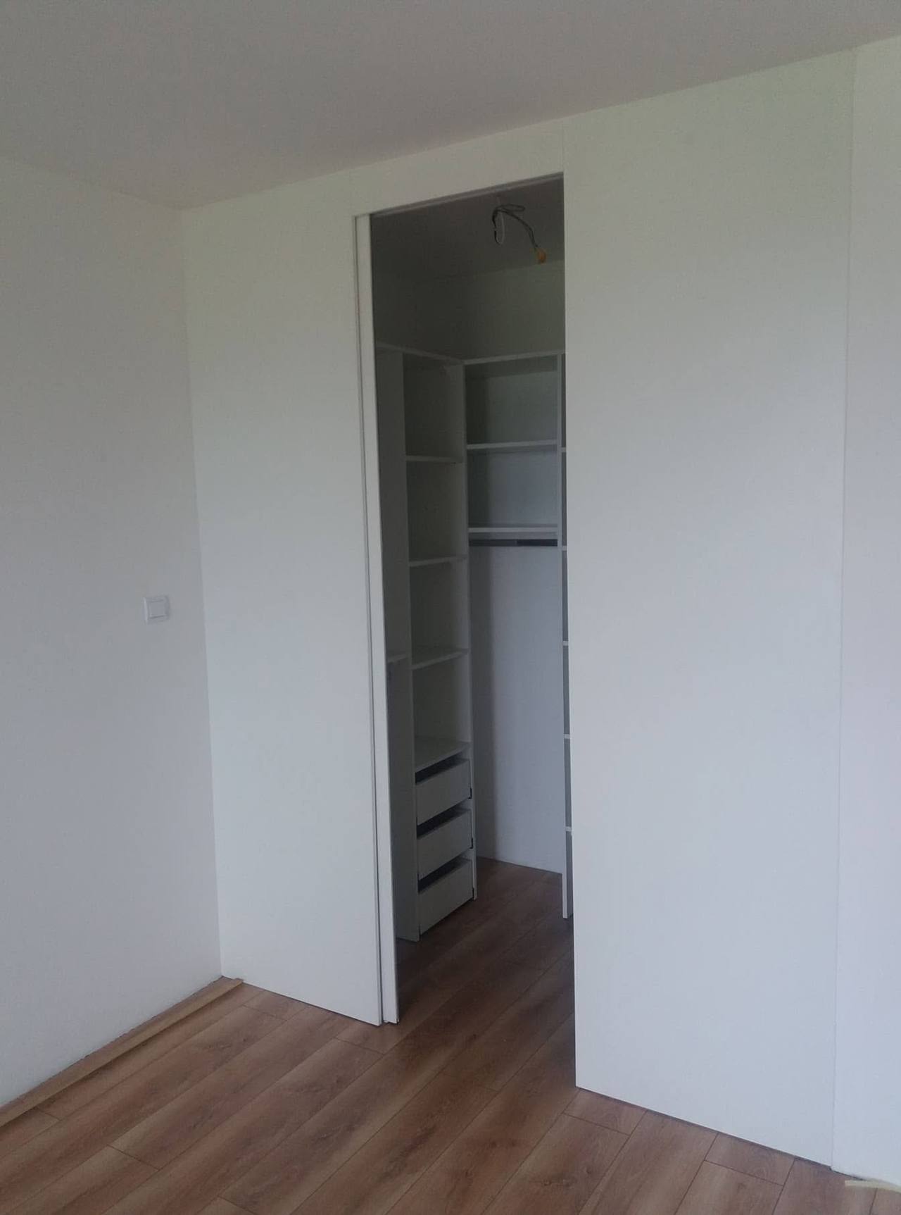 Vysoký vstup do bieleho šatníka v izbe s drevenou podlahou