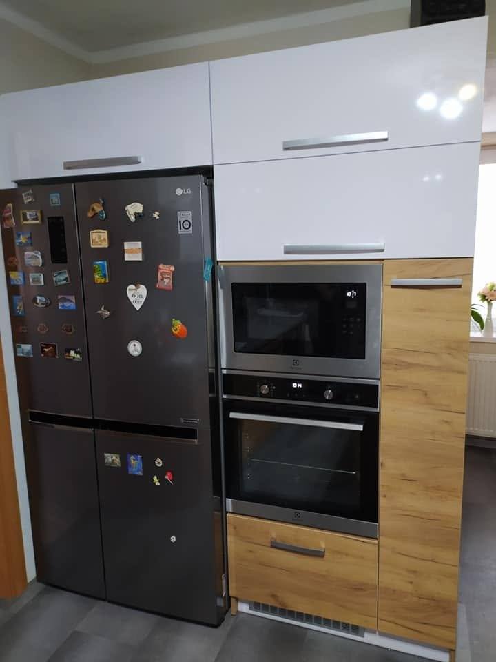 Hoher Schrank in Eichendekor mit Einbaubackrohr neben dem Side-by-Side-Kühlschrank.