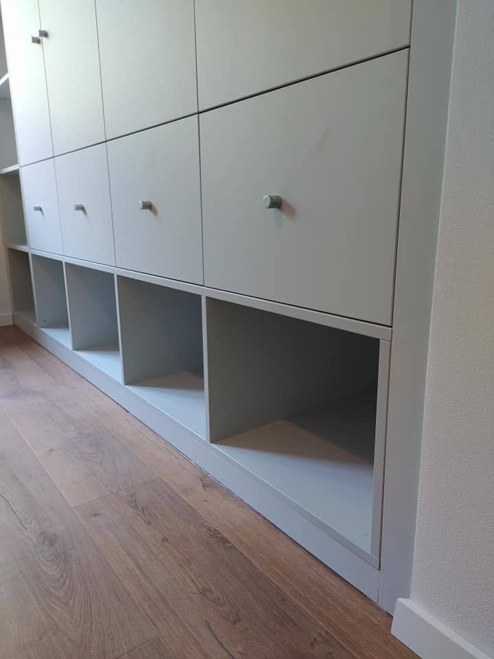 Heller hoher Kasten mit Türen oben und offenen Schuhfächern unten.