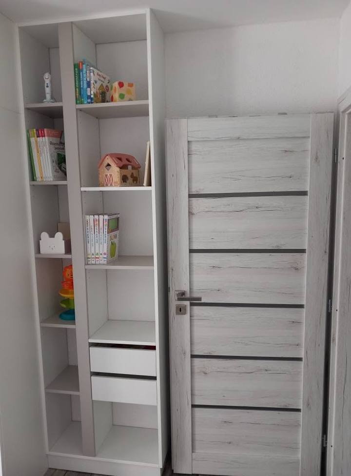 Hohes weißes Regal mit Laden neben der Kinderzimmertür