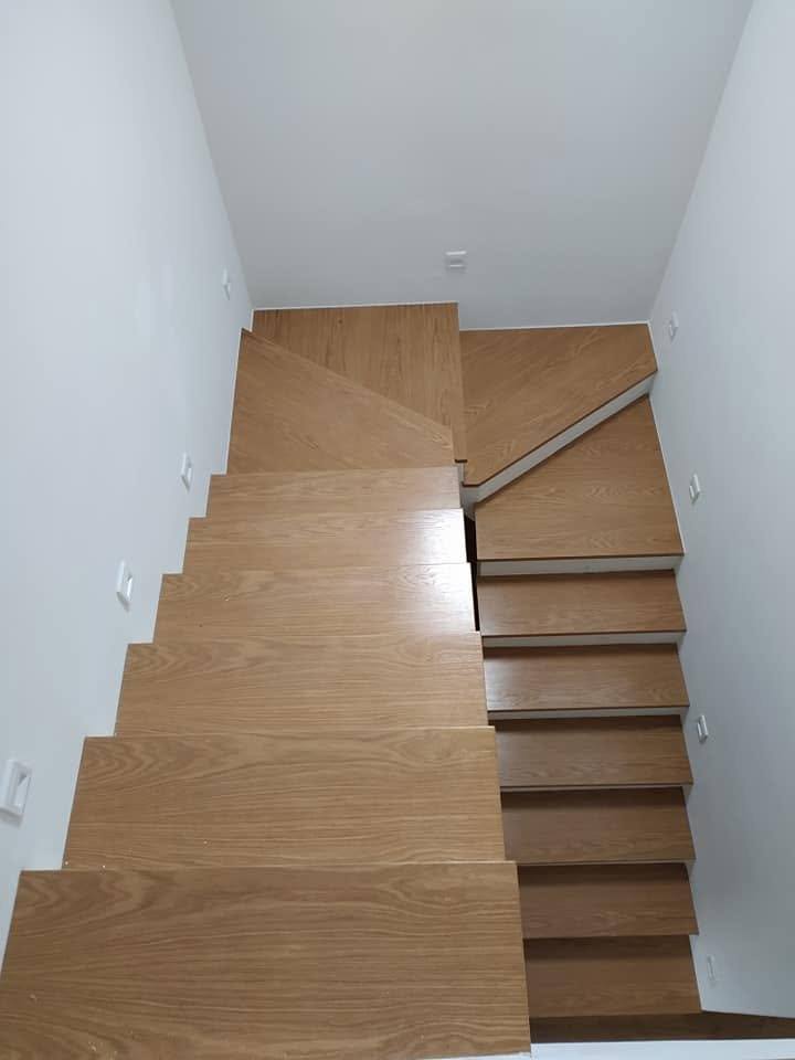 Verwinkelte Stiege mit schwarzem Handlauf vom oberen Podest aus
