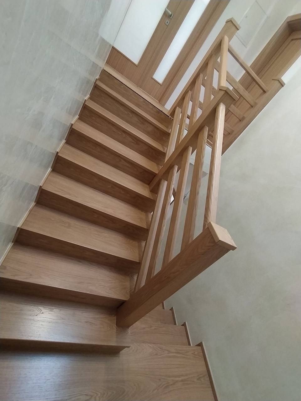 Verwinkelte Eichenstiege mit Holzgeländer vom oberen Podest gesehen