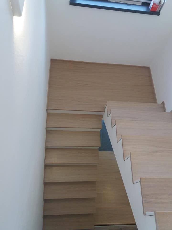 Verwinkelte Stiege in heller Eiche mit Podest von unten gesehen