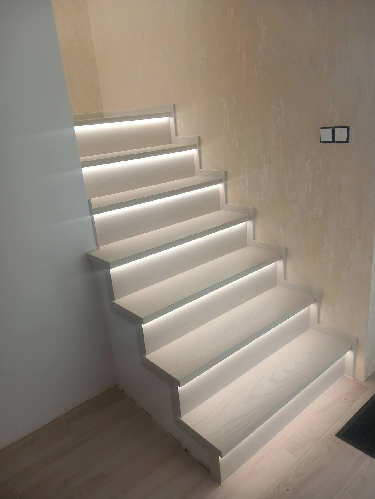 Helle Stiege mit beleuchteten Stufen an der Wand