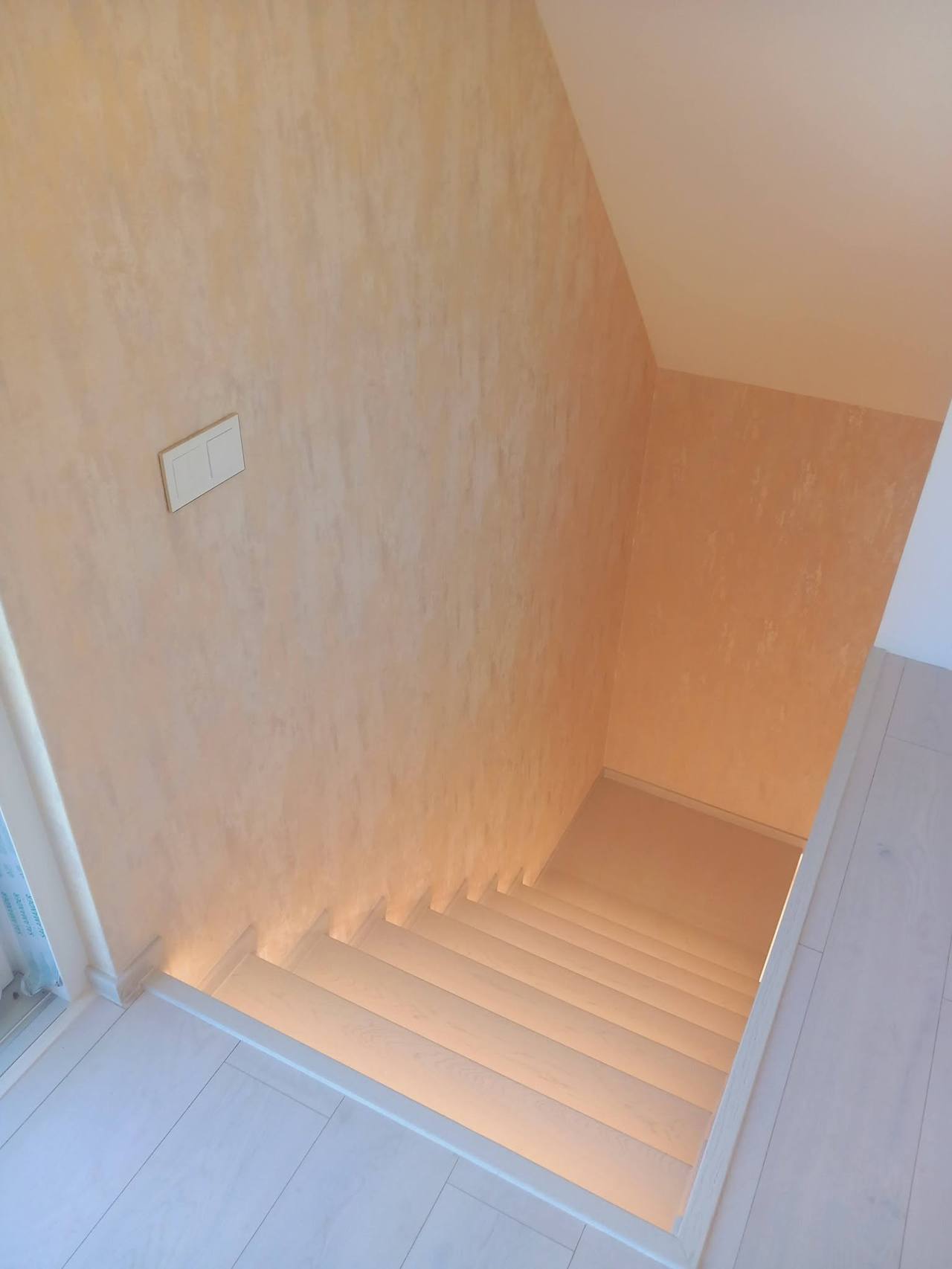 Beleuchtete Stiege von oben in den Gang gesehen