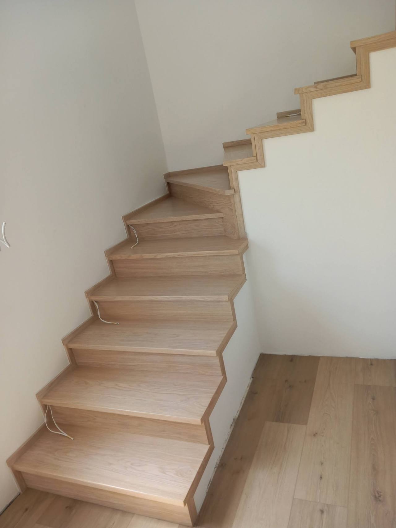 Helle Eichenstiege mit Drehung entlang der weißen Wand