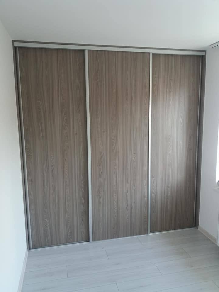 Geschlossener dreitüriger Schiebetürkasten in graubraunem Holzdekor.