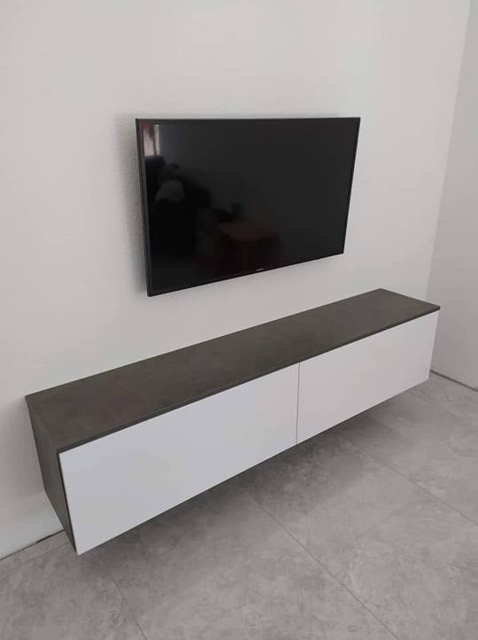 Hängeelement mit weißen Türen und dunklem Rahmen unter dem Fernseher