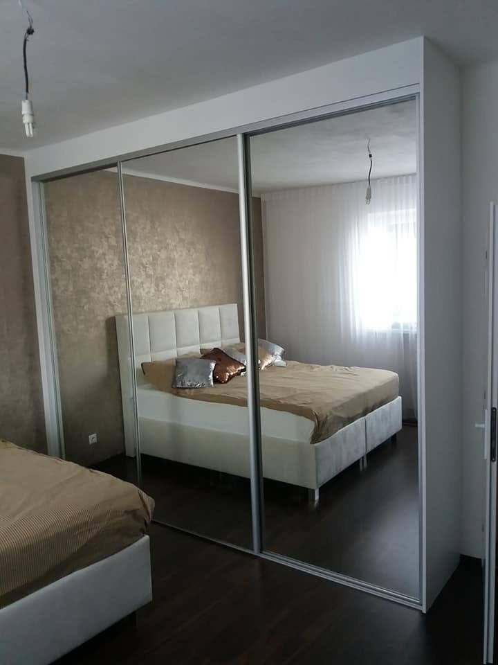 Spiegel-Schiebetürkasten mit Spiegelung des Schlafzimmers und gepolstertem Bett.